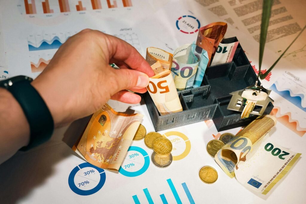 Maketa kuće s novčanicama eura, ključevima i financijskim grafikonima kao prikaz diverzifikacije investicija