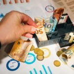 Maketa kuće s novčanicama eura, ključevima i financijskim grafikonima kao prikaz diverzifikacije investicija